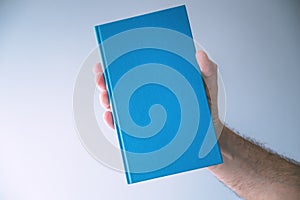 Blue hardcover book mockup, man holding book