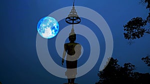 Blue harvest moon moving on night sky and silhouette buddha