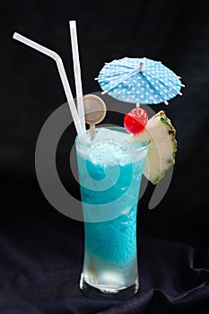 Blue Hawaii cocktail Tall glass with umbrella with pineapple and red cherries.Suitable for drinking for refreshing, quenching