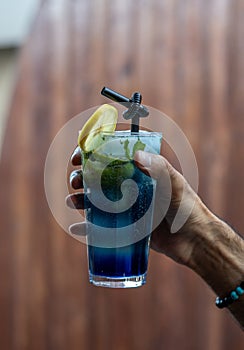 Blue Hawaiian Cocktail in a glass with a straw, lime and mint