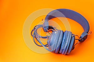 blue headphones with cable and black 3.5 jack on orange background