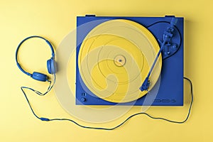 Blue headphones and a yellow-blue vinyl record player on a yellow background