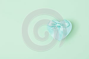 Blue heart shape decorative gift box with blue bow on mint green background. Valentine`s day, love, wedding,