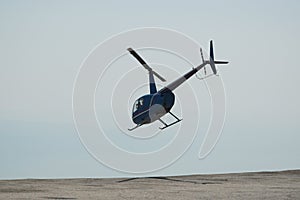 Blue helicopter flying in grey cloudy skies