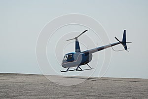 Blue helicopter flying in grey cloudy skies