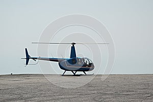 Blue helicopter flying in grey cloudy skies