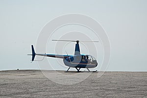 Blue helicopter flying in grey cloudy skies