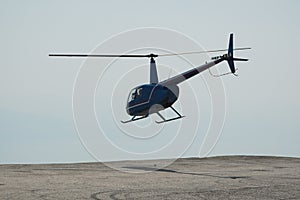 Blue helicopter flying in grey cloudy skies