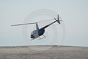 Blue helicopter flying in grey cloudy skies