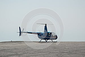 Blue helicopter flying in grey cloudy skies