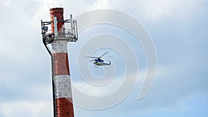 Blue helicopter passing over roof next to chimney