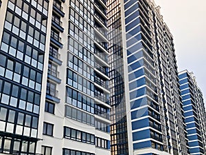 Blue high modern monolithic frame building, house, new building, a skyscraper with mirrored windows against a blue sky.