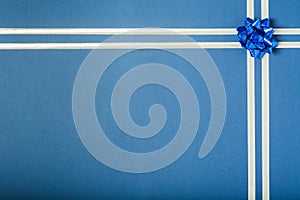 Blue holiday background for gift with silver ribbon and blue bow in corner