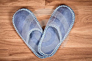 Blue home slippers on a brown wooden floor