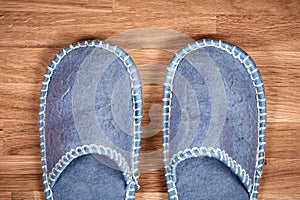 Blue home slippers on a brown wooden floor