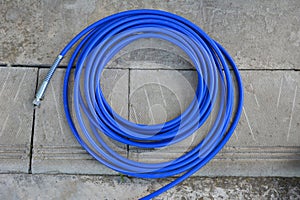 The blue hose of the spray gun is lying on the concrete