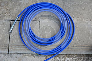 The blue hose of the spray gun is lying on the concrete