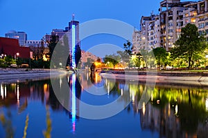 Blue hour light reflections in the city, on Dambovita river, in Bucharest, Romania. Tall building Chamber of Commerce and Industry