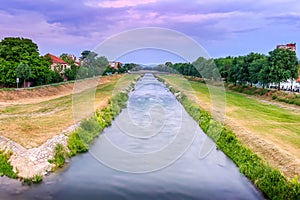 Blue hour Nisava river and promenade in Pirot with silky, blurred motion water, cloudy sky