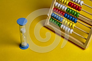 Blue hourglass and abacus at yellow background. Time management concept, time is money concept