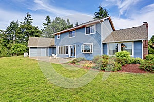 Blue house backyard with concrete floor patio area and well kept garden.