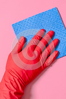 Blue house cleaning sponge in hand in red rubber glove on red background