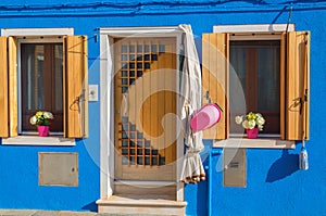 Blue house with flowers on sills in Burano, Venice