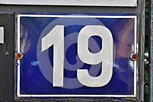 A blue house number plaque, showing the number nineteen