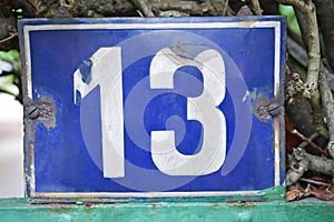 A blue house number plaque, showing the number thirteen