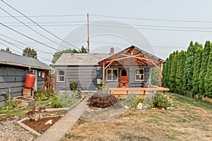 Blue house with red door backyard with deck and pergola and dead grass with garden