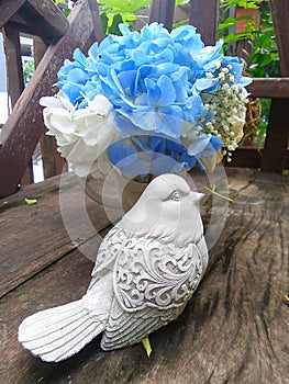 Blue Hydragea flower and bird sculpture on wooden bench