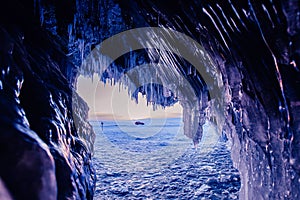 Blue Ice cave or grotto on winter lake Baikal. Beautiful winter landscape with long icicles