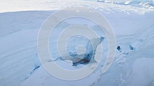 Blue ice cave in white glacier on Antarctic Peninsula. Aerial shot close-up.