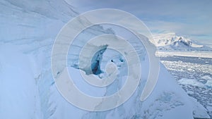 Blue ice cave in white glacier on Antarctic Peninsula. Aerial shot close-up.