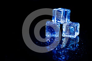 Blue ice cubes reflection on black.