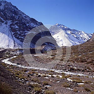 blue ice-free river flows in a snow-covered valley. Thawed ice floes are visible in the stream. Reflection. A picturesque