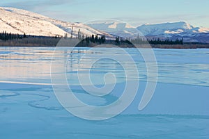 Blue ice of the frozen lake at morning. Winter landscape in the mountains and the winter road in Yakutia, Siberia, Russia