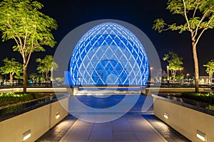 Blue illuminated sphere dome located next to Sheikh Zayed Grand Mosque in Abu Dhabi UAE, shot at night.