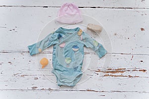 Blue infant bodysuit made of organic cotton with eco-friendly baby accessories on white background