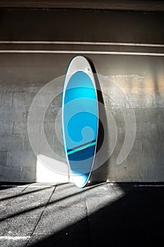 Blue inflatable stand-up paddle board SUP by the wall. Surfing and sup boarding equipment close up photo