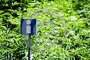Blue information sign with green garden background