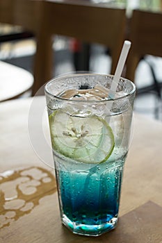 Blue Italian soda on wood bar in cafe, selective focus