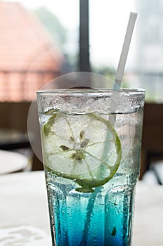 Blue Italian soda on wood bar in cafe, selective focus