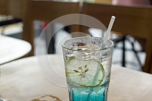 Blue Italian soda on wood bar in cafe, selective focus