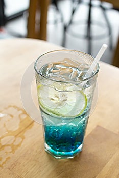 Blue Italian soda on wood bar in cafe, selective focus