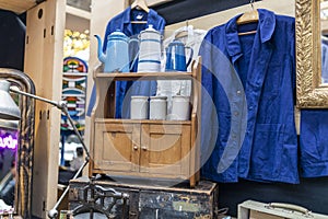 blue jacket, white cans for bulk products on a small light chest of drawers from the seventies at an antique market