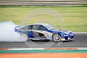 Blue Japanese sports car Nissan Silvia S13 producing smoke on a trail for a drift competition