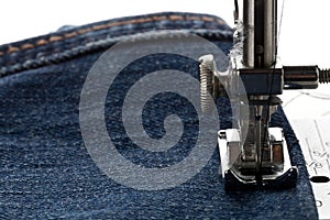 Blue jeans denim sewed on sewing machine close up - jeans fashion mending or repair concept