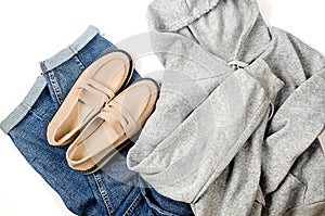 Blue jeans, gery hoody, beige suede loafer or flat shoes lying on white background