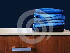 Blue jeans isolated on blue background. Jeans stacked on a light background. Jeans background. Stack of clothing  close up.